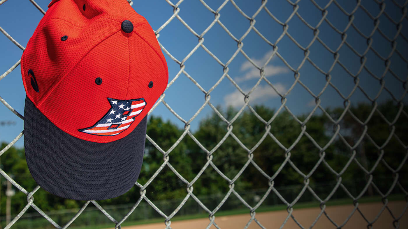 Youth Baseball hat hanging on dugout fence