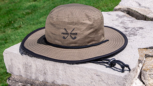 Bucket Golf sun hat on a stone wall
