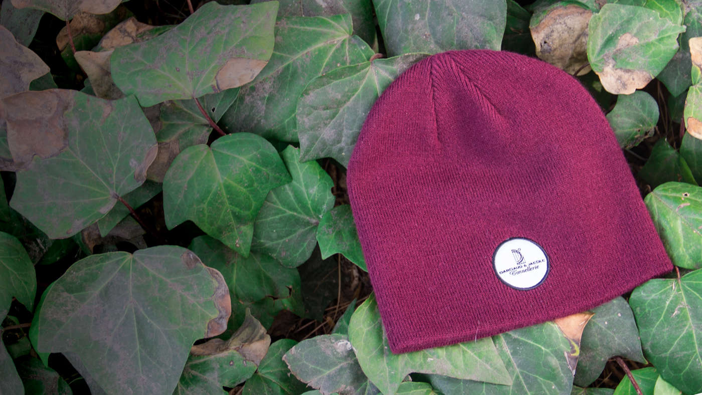 Uncuffed Knit hat laying on bed of green ivy